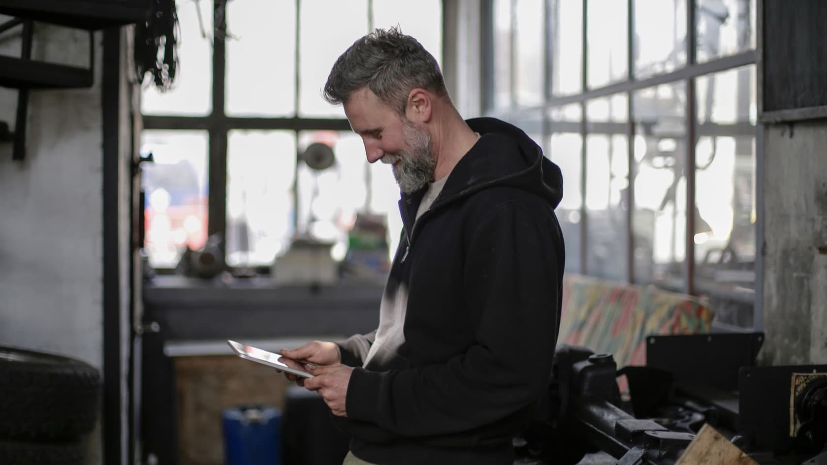 Technician reading a tablet at his workbench in a busy workshop