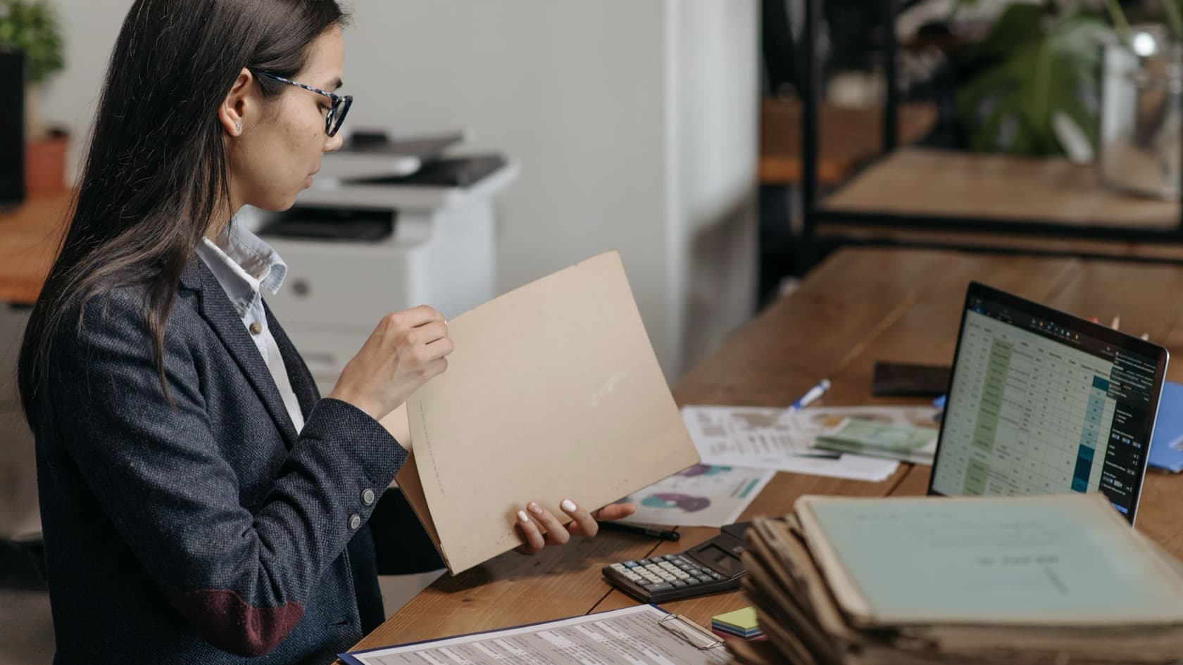 Buyer comparing paper quotes against a spreadsheet on her laptop