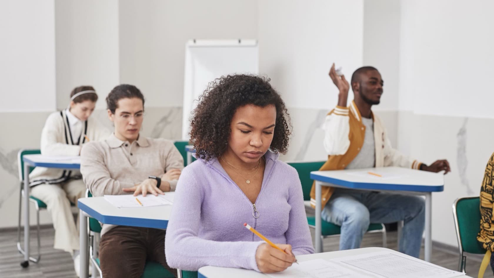 Candidates writing an assessment at desks in a bright exam room
