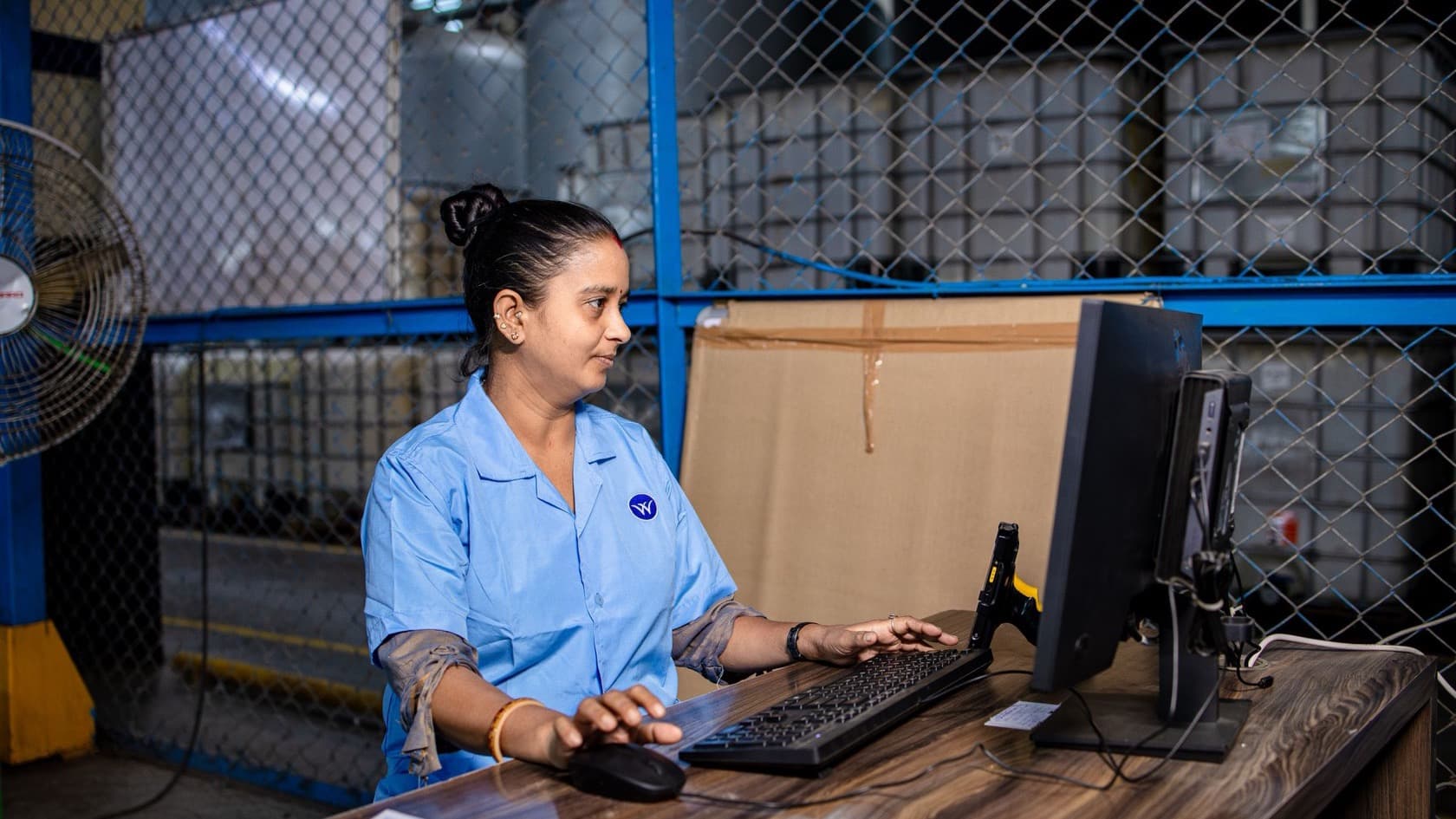 Plant worker entering records at a computer with a barcode scanner