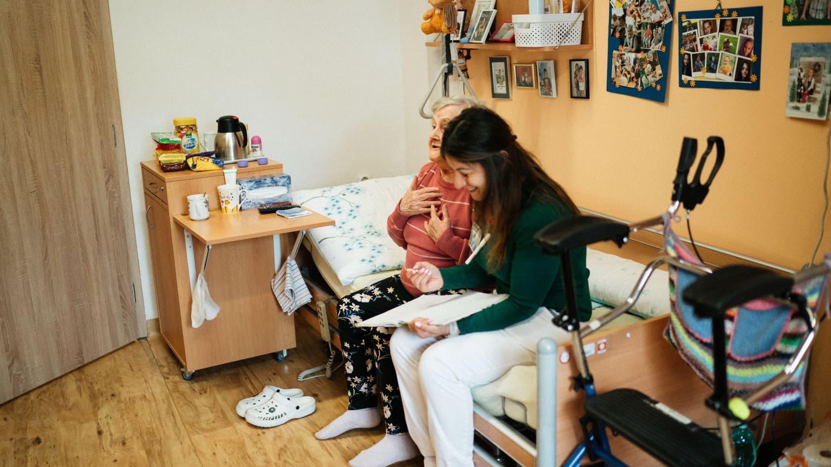 Carer sitting with an older resident on her bed, going through papers together