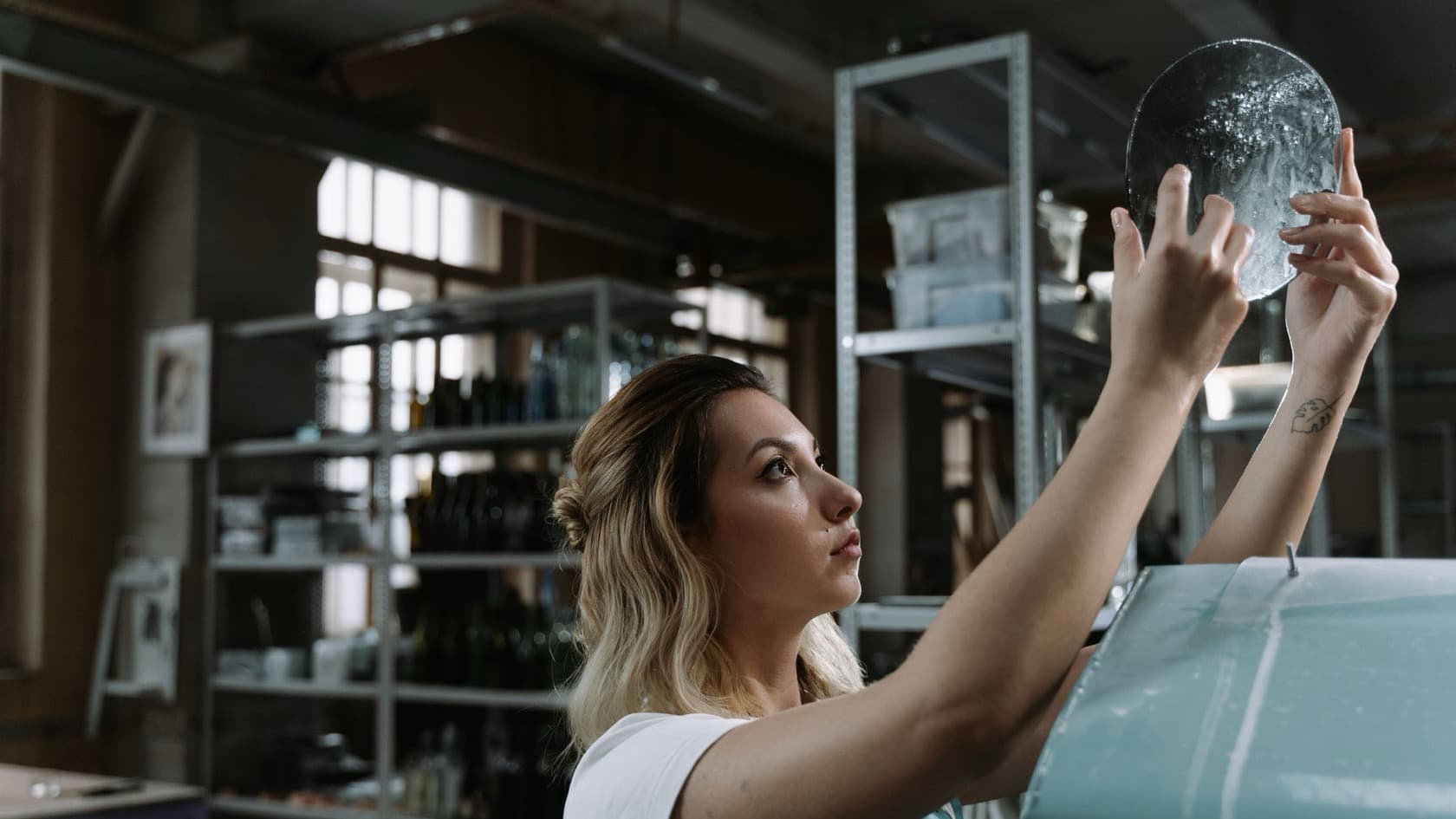 Worker holding a piece of glass up to the light to check it for flaws in a glass workshop