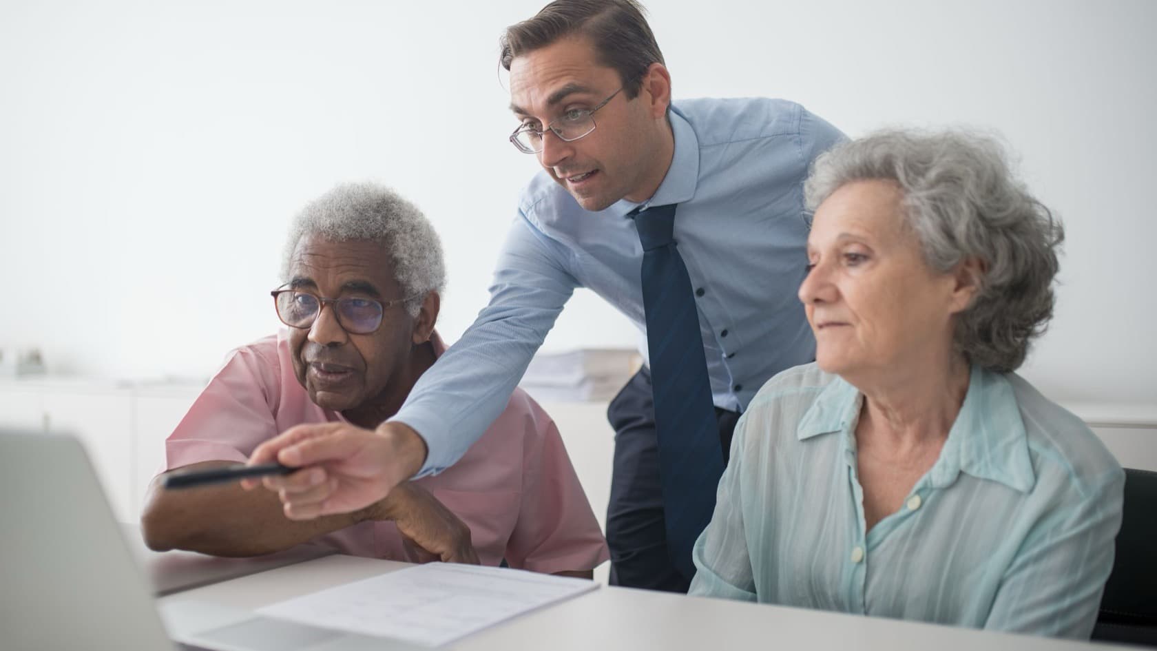 Advisor pointing out details on a laptop to an older couple at a table