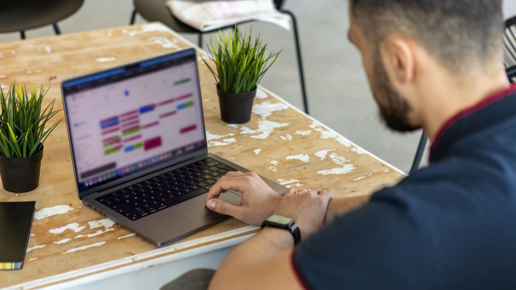 Organizer working through a color-coded schedule on a laptop at a shared table