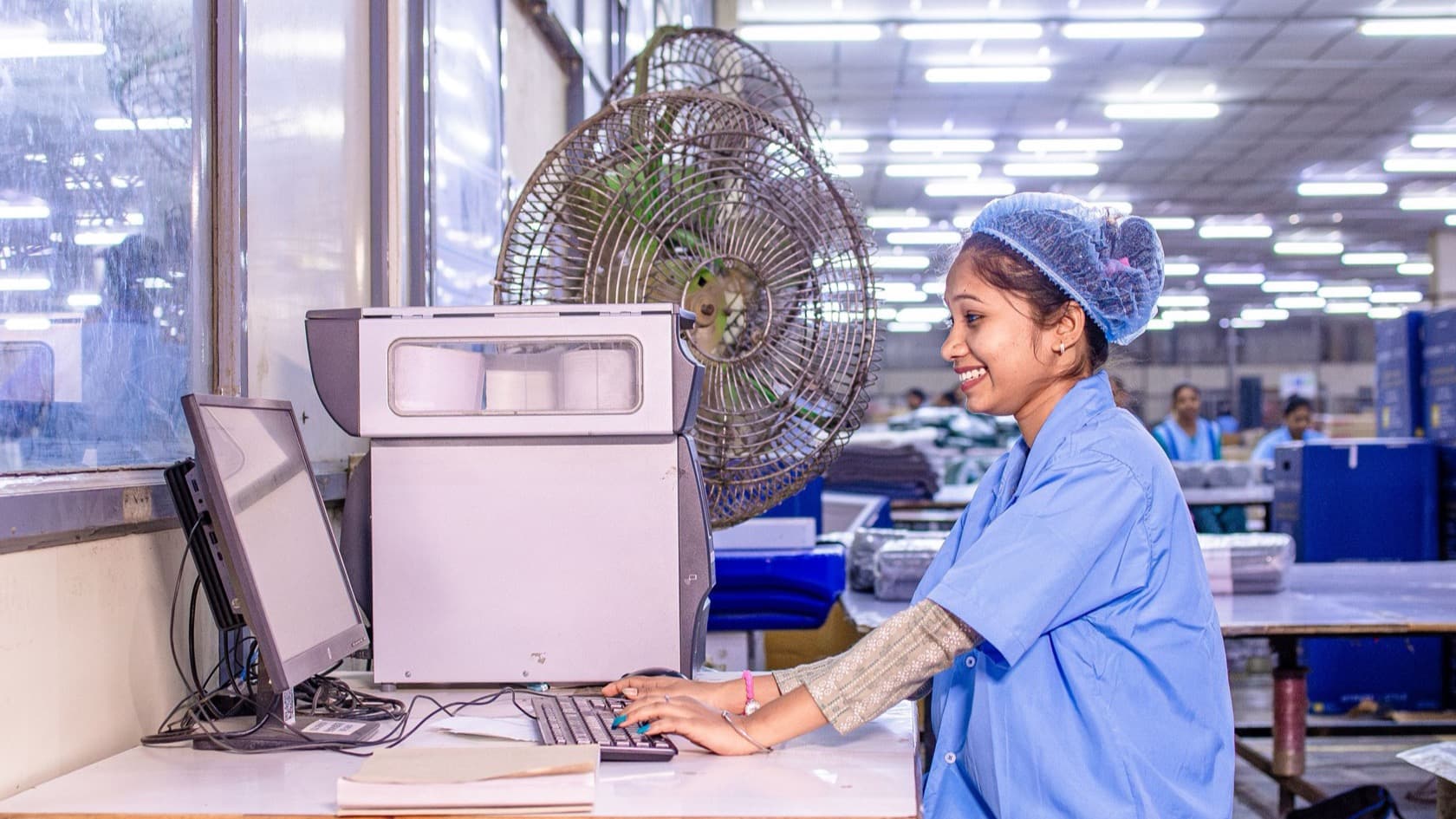 Factory worker in a hairnet looking something up on a shop-floor computer