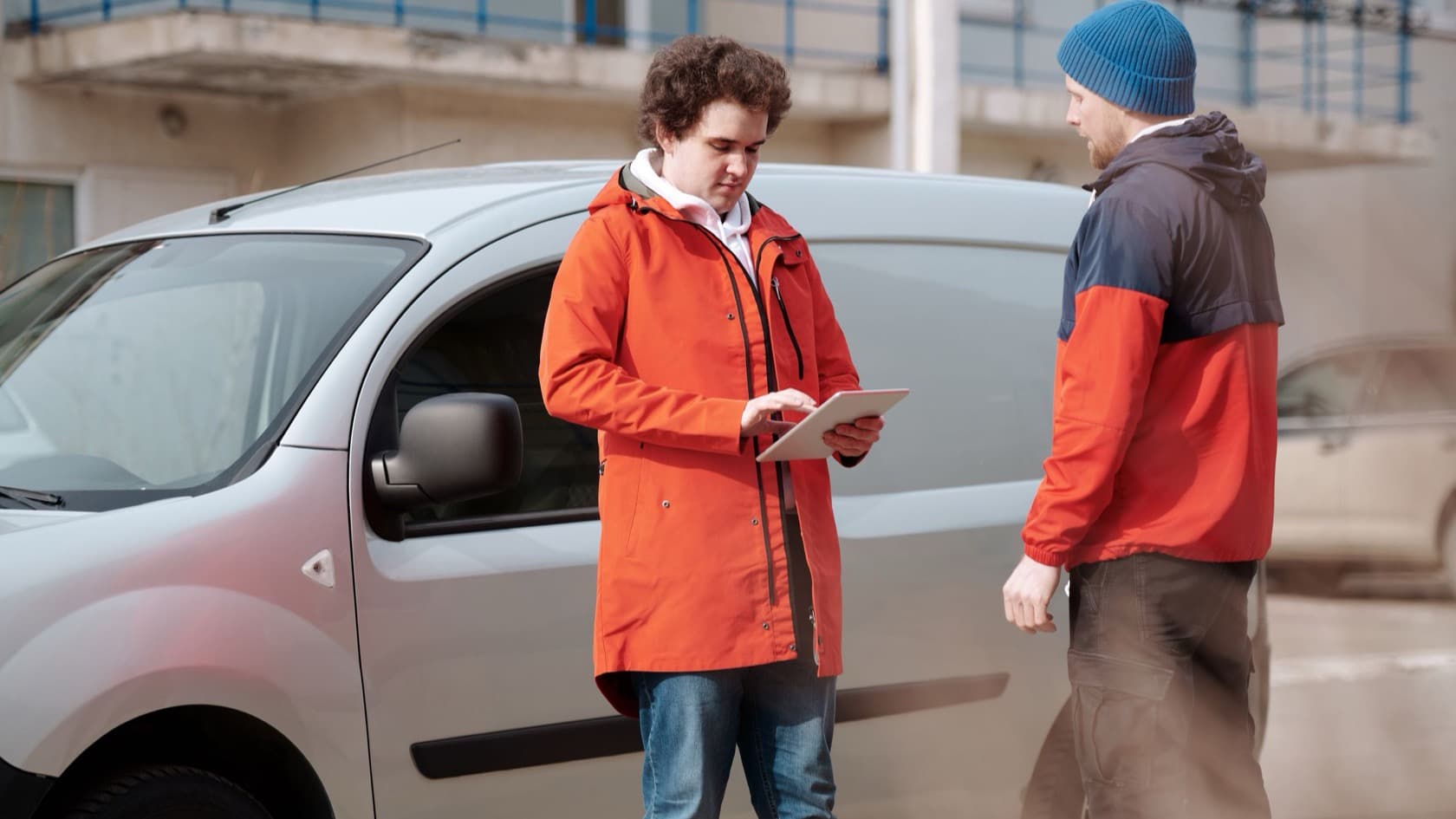 Two delivery workers checking a shipment on a tablet beside a van