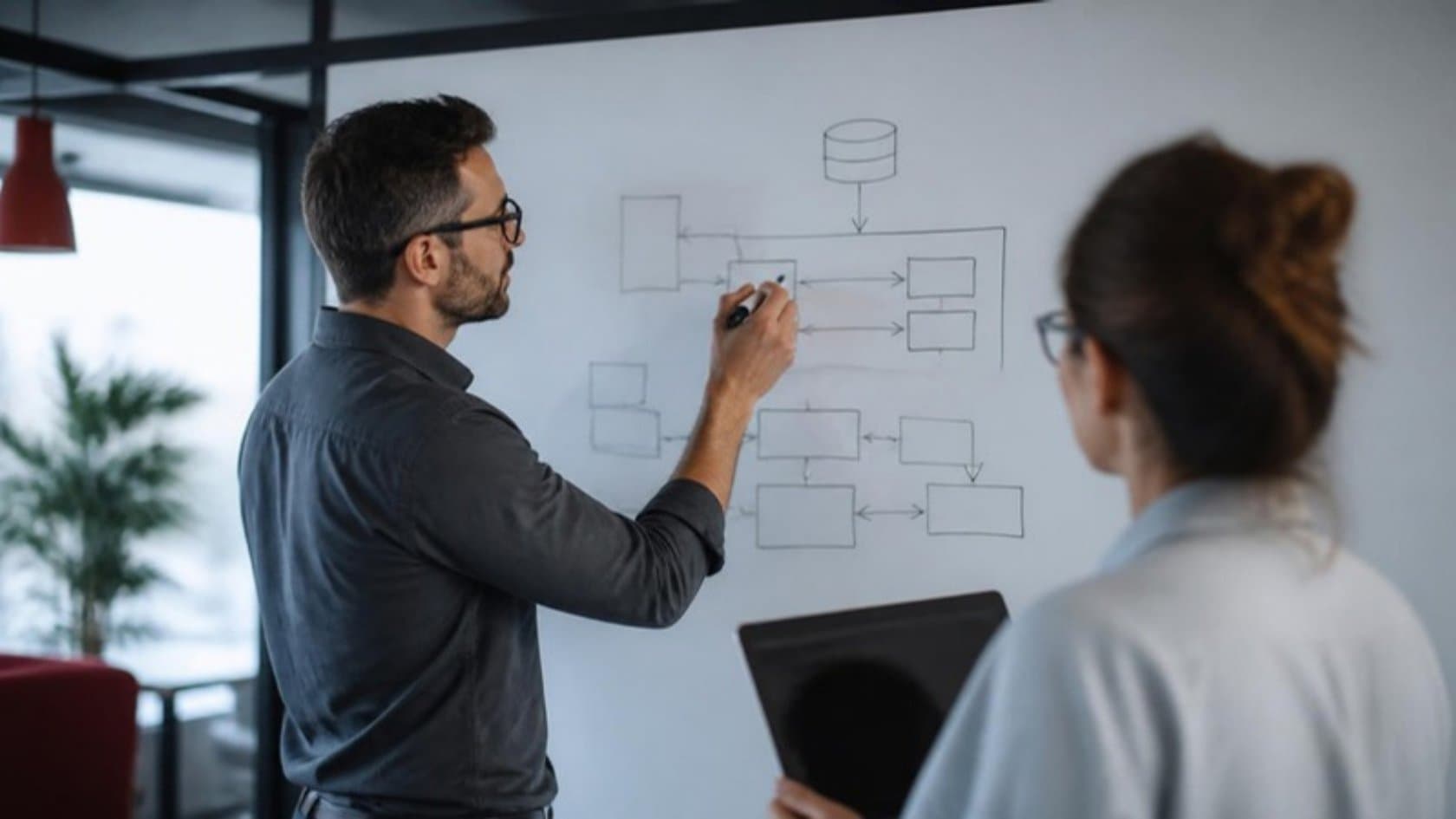 Software architect drawing a web application architecture diagram on a whiteboard