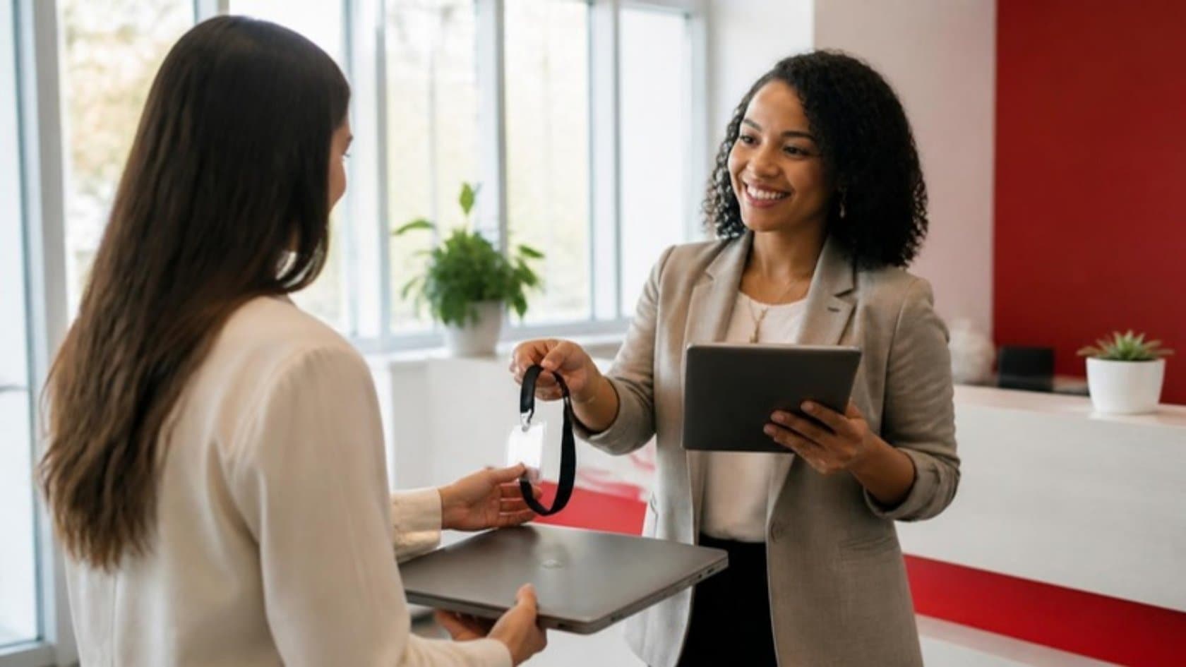 HR coordinator handing a new employee a laptop and access badge on their first day