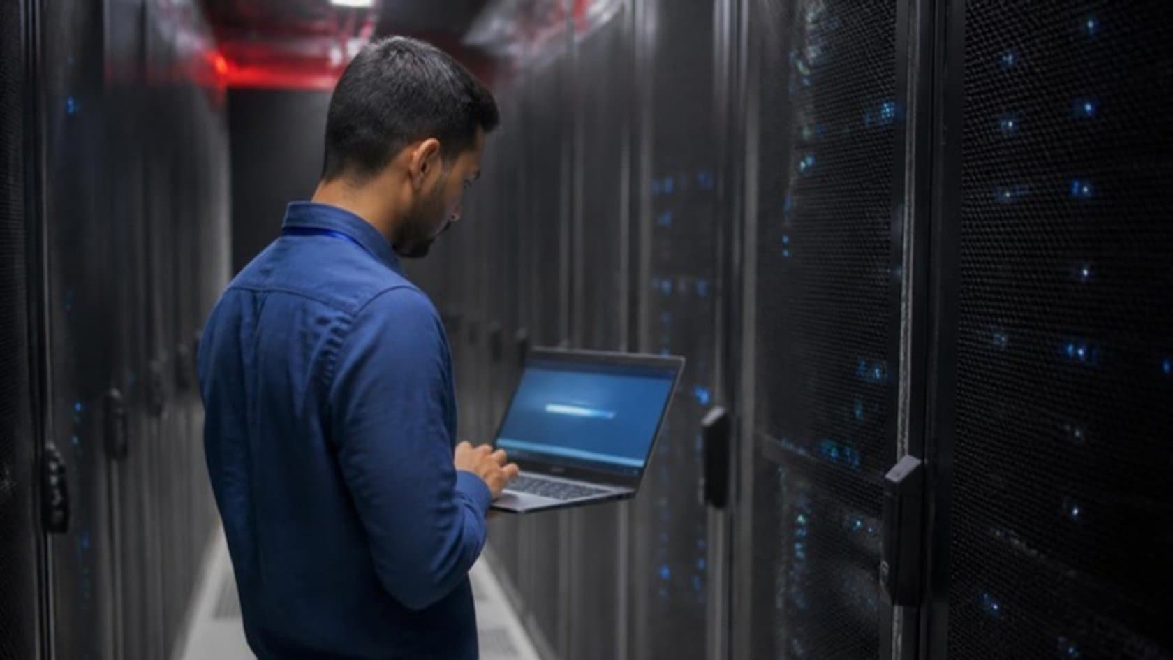 Engineer with a laptop in a data center aisle checking a legacy application's cloud migration