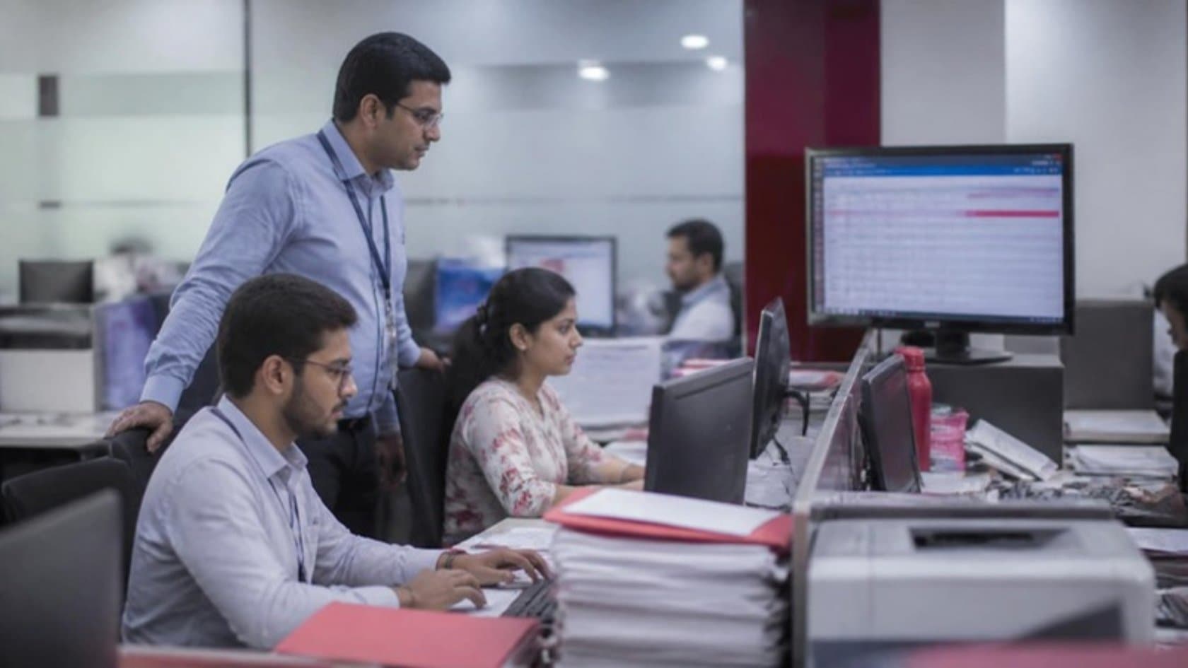 Bank back-office staff processing loan documents while a team lead reviews the queue