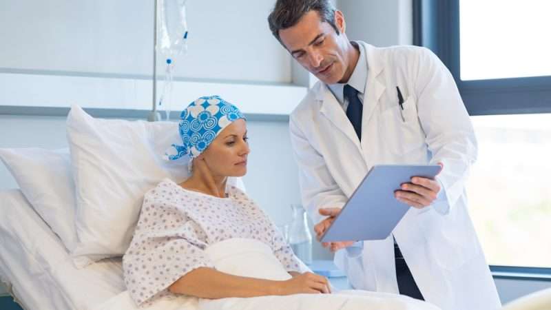 Doctor showing a patient information on a tablet beside her hospital bed